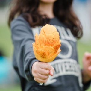 Person holding a fresh mango from Mexico, peeled and ready to eat on a stick with tajin.
