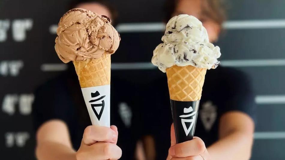 The scene also includes two girls holding gelatos on waffle cones. The tags associated with the image are ice cream, dairy, food, dessert, person, ice cream cone, frozen dessert, gelato, snack, holding, and indoor.