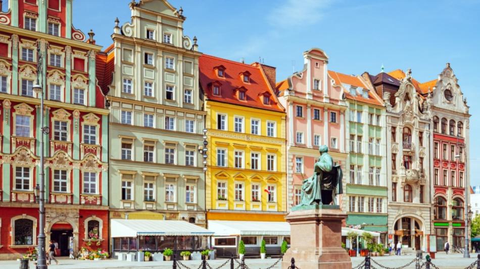 The photo is of a statue in front of a building in Wroclaw, Poland. The building appears to be historic tenements on the main square.
