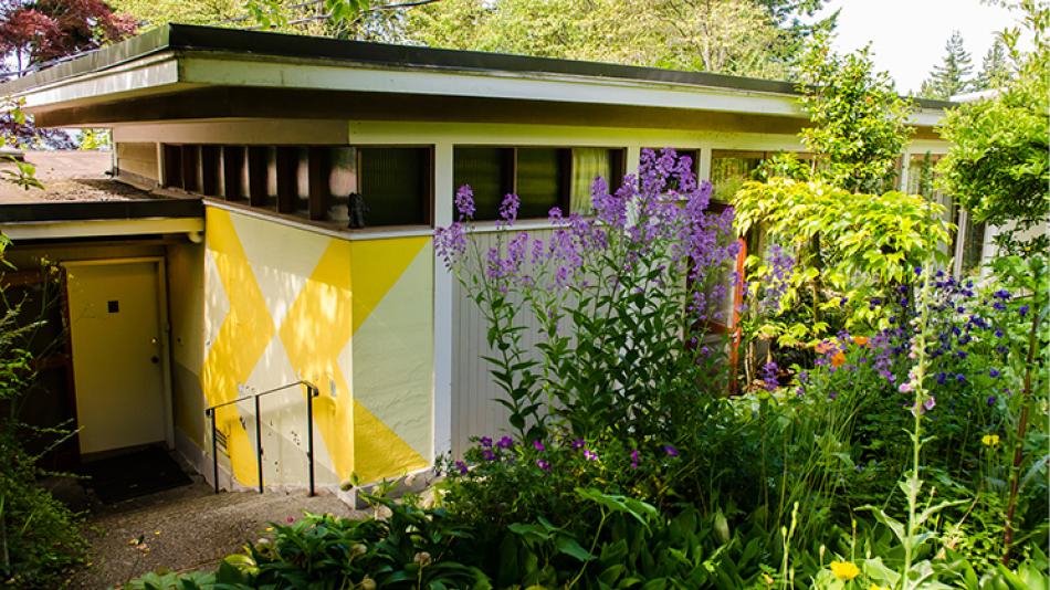 The Binning Residence entrance, set into the ground and surrounded by foliage.