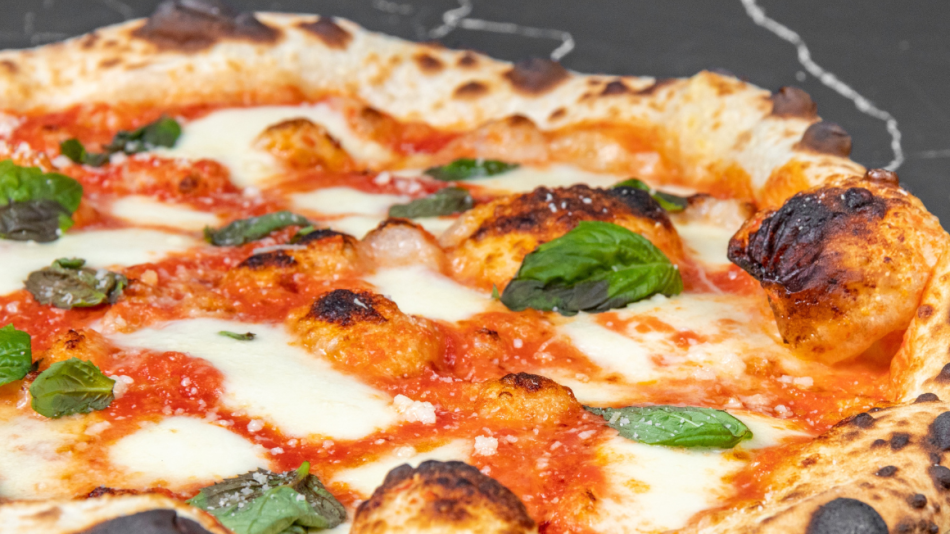 The image is a close-up, overhead shot of a Neapolitan-style pizza. The pizza is the primary focus and fills most of the frame, positioned slightly off-center to the right.