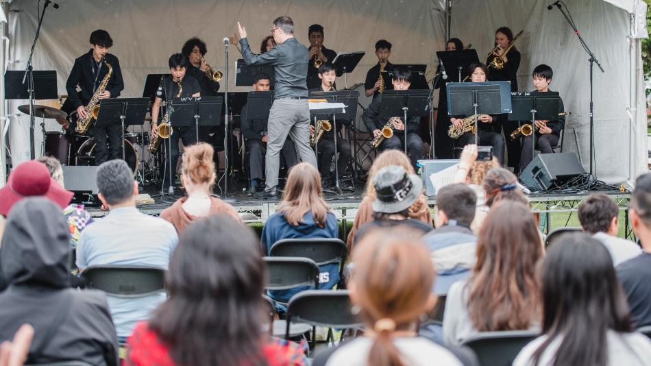 A lively band performs on stage while an enthusiastic crowd watches and enjoys the music.