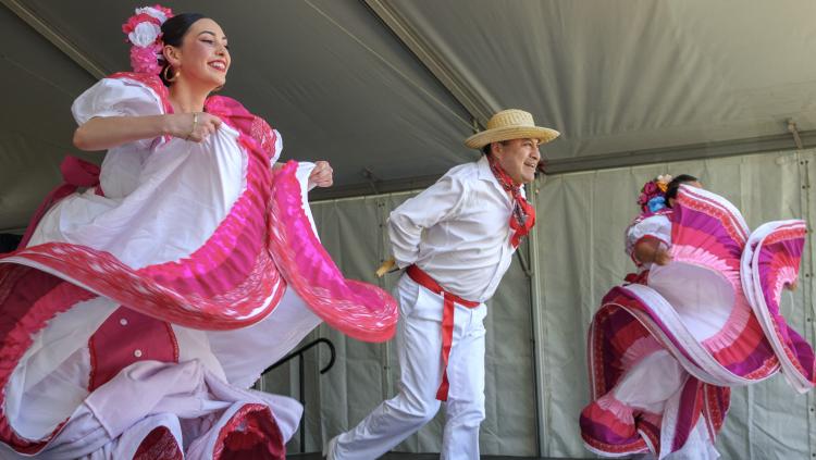 A lively group of individuals in colorful Mexican costumes joyfully dancing together in a festive atmosphere.
