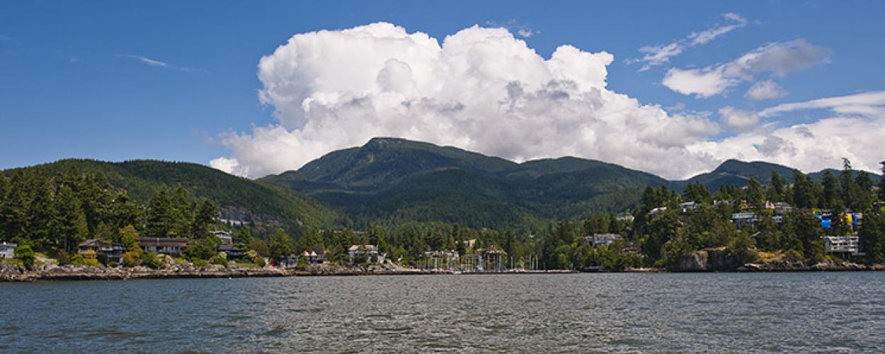 From across a lake, a waterfront village sits at the base of some mountains. 