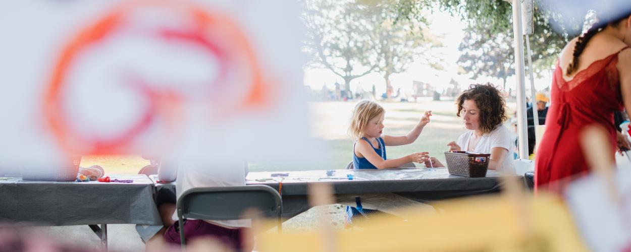 A woman and a children gather around a table doing kids craft activities