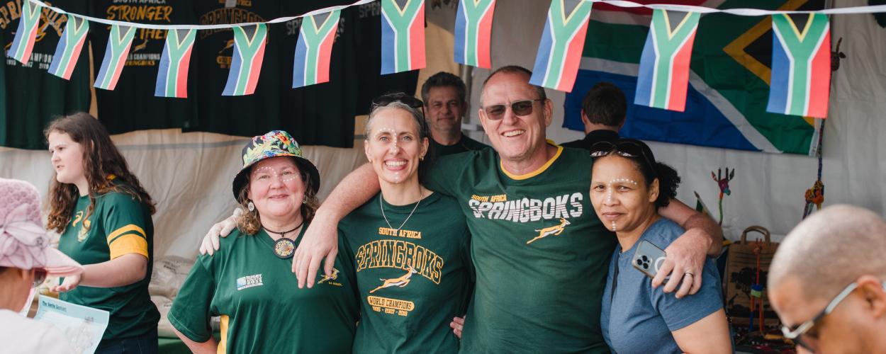 A group of individuals in green shirts, proudly holding flags, gathered together in a display of unity and enthusiasm.