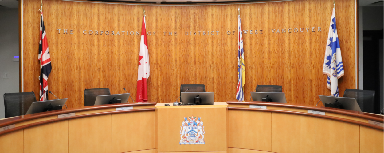 The District of West Vancouver Council chambers. Five Council seats are visible.