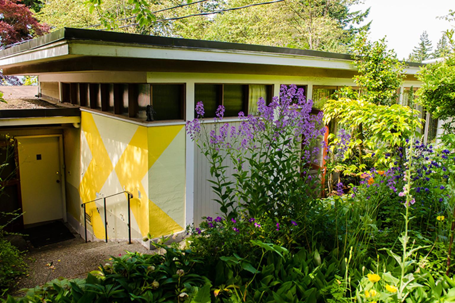 The Binning Residence entrance, set into the ground and surrounded by foliage.