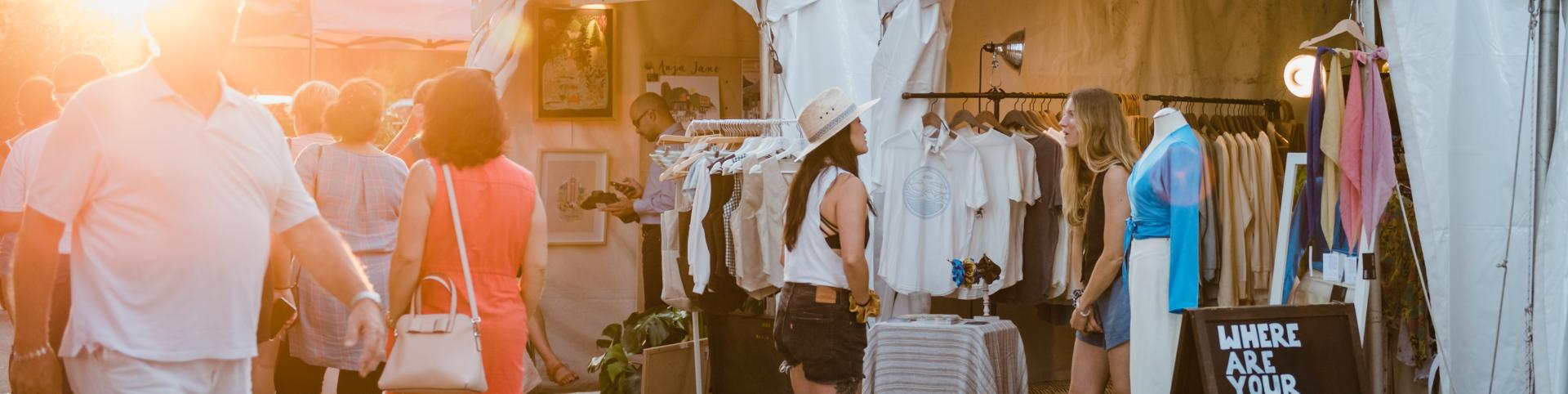 A group of shoppers navigating through a busy market, engaging with vendors and exploring various products.