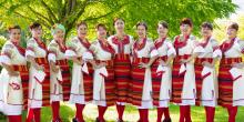 A group of women from Kitka, Hubavitz, and Duo Balkanaria posing together in colorful traditional costumes for a photo.